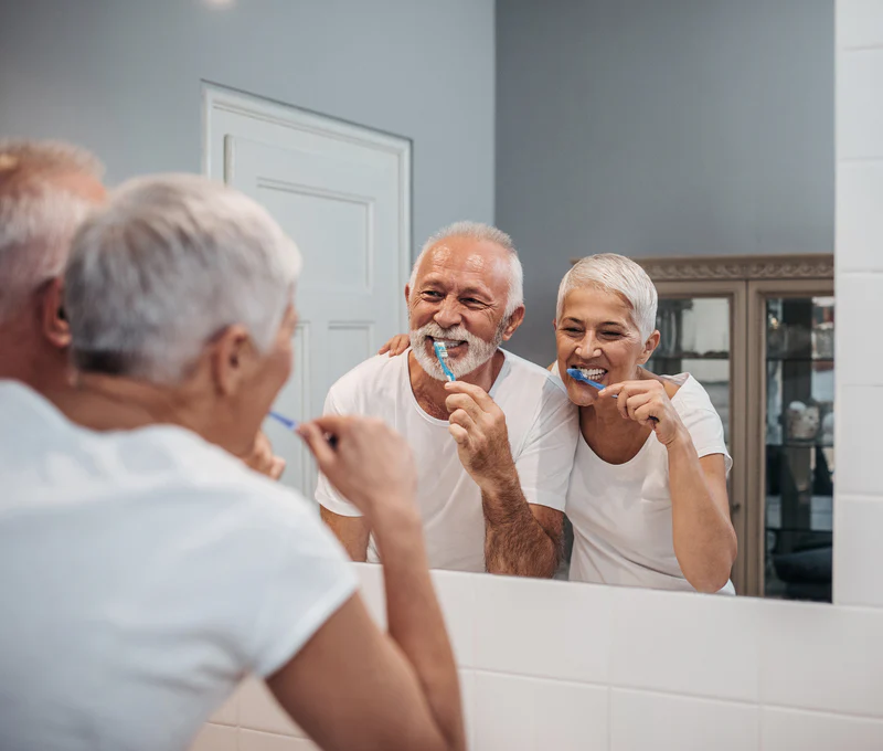Älteres Paar putzt gemeinsam Zähne vor einem Spiegel in einem Badezimmer.