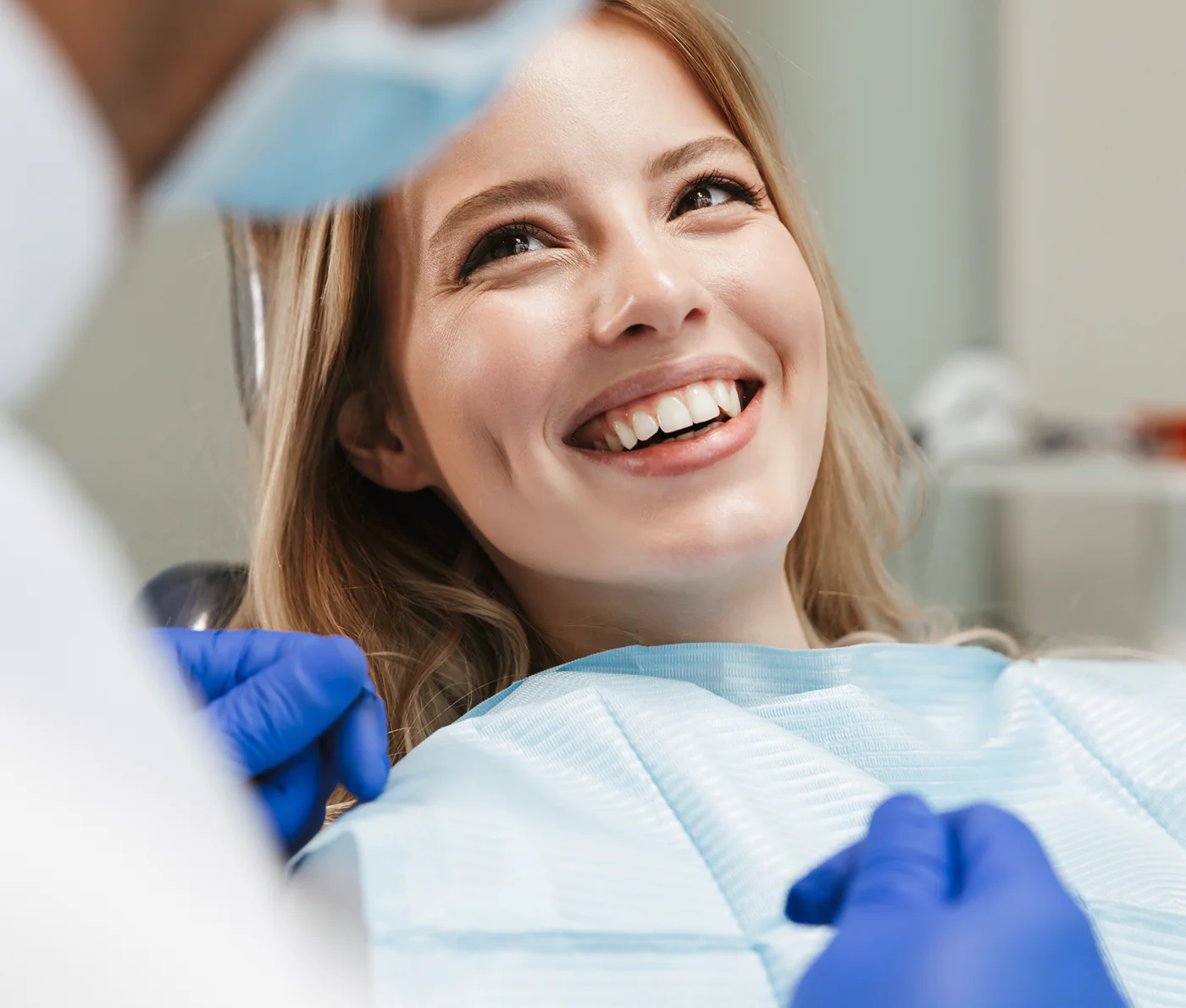 Junge Frau mit lächelndem Gesicht während einer zahnärztlichen Behandlung ohne Instrumente.